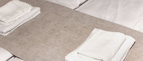 Une chambre d’hôtel avec un lit, des oreillers, une table de chevet avec une lampe et une plante.