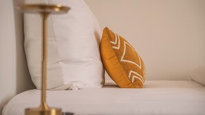 A white sofa with a single brown pillow featuring a geometric pattern.