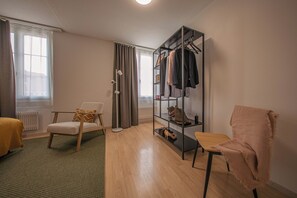 A modern living room with a sofa, a chair, a bookshelf, and a radiator. - Gasthaus Hirschen (Hinwil)
