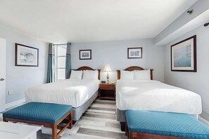 A hotel room with two beds, a desk, and a chair. There are framed pictures on the walls and a window with curtains. - Carolinian Beach Resort 1230 (Myrtle Beach)