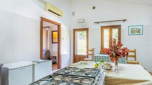 A kitchen with a gas stove, a refrigerator, and a dining table with a vase of flowers. - Farmhouse with pool between Orvieto and Todi (Montecchio)