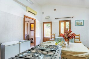 A kitchen with a gas stove, a refrigerator, and a dining table with a vase of flowers. - Farmhouse with pool between Orvieto and Todi (Montecchio)