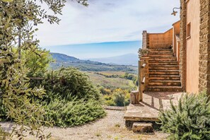 Un escalier en pierre mène à un bâtiment d’où l’on peut admirer un paysage vallonné.
