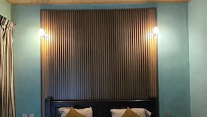 A bedroom with a large bed, two bedside tables, a wooden headboard, and a ceiling with a skylight.