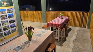 An outdoor dining area with a table and benches, a map on the wall, and a view of the sky.