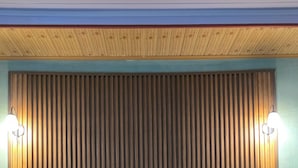 A hotel room with a large bed, two pillows, a wooden headboard, and a slatted wall panel.