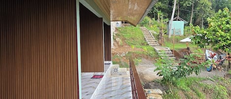 A wooden ceiling with a skylight, a marble floor with a doormat, and a view of a garden with a staircase.