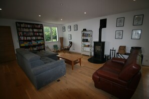Una sala de estar con sofá, sillón, estantería y chimenea.