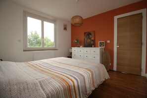 A bedroom with a large bed, a dresser, a fan, and a door. - 100-square-meter apartment in a quiet location right in the heart of town (Saint-Pée-sur-Nivelle)