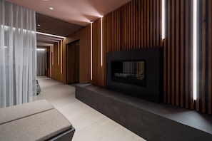 A modern interior with a built-in fireplace, wooden paneling, and a seating area. - Elegant Apartment With Sunny Loggia (Lübeck)
