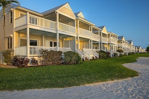 A row of beachside bungalows with balconies, a sandy walkway, and a clear blue sky. - Amazing Stay in the Middle of Florida Keys! Amazing View from Balcony (Duck Key)