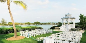 A wedding ceremony setup with white chairs arranged in rows, a white gazebo, and a palm tree. - Amazing Stay in the Middle of Florida Keys! Amazing View from Balcony (Duck Key)