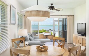 Ein modernes Zimmer mit Balkon, Deckenventilator, Fernseher und Meerblick.