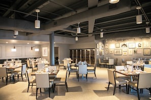 A spacious restaurant with multiple dining tables and chairs, overhead lighting, and framed artwork on the walls. - Amazing Stay in the Middle of Florida Keys! Amazing View from Balcony (Duck Key)