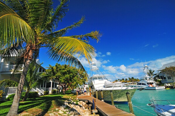 A marina with boats docked, a wooden walkway, and a house with a balcony. - Perfect for Family and Friends — Gorgeous Villa with Full Kitchen, & Pool Access (Duck Key)