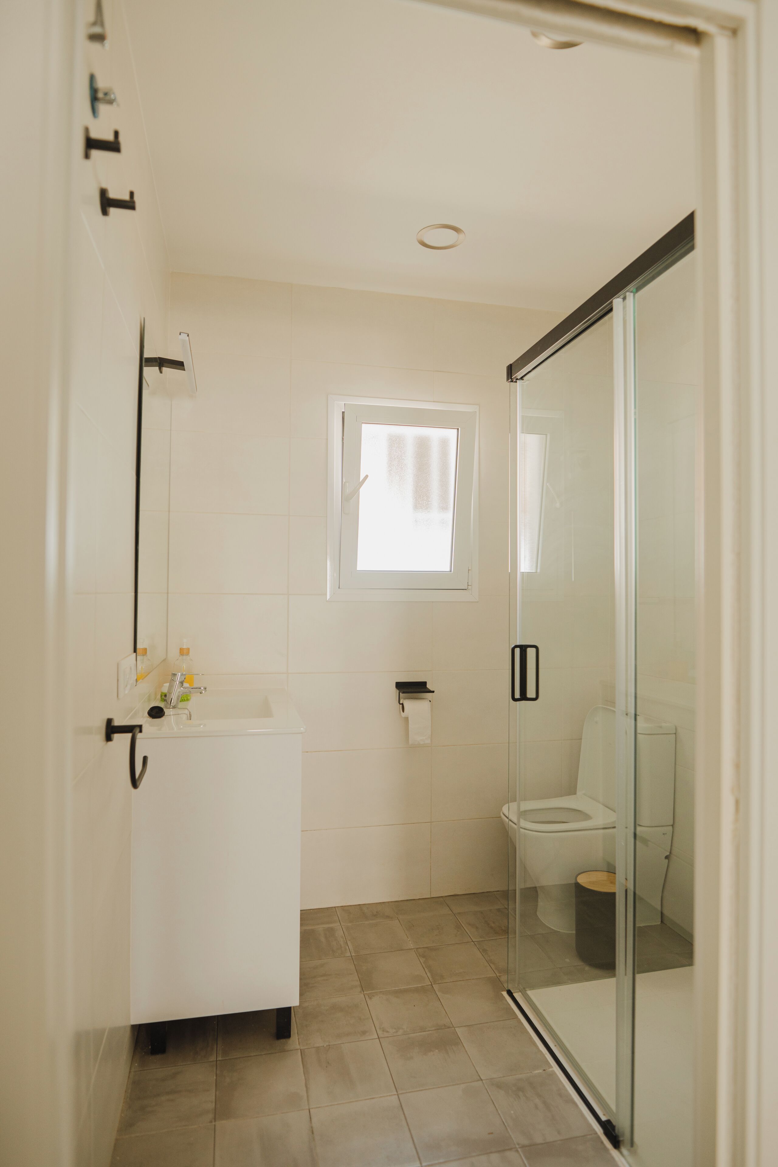 A bathroom with a glass shower enclosure, a white sink, and a toilet.