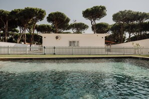 A swimming pool with a white fence and trees in the background. - Villa Los Gallos (Chiclana de la Frontera)