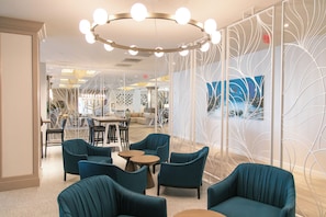 A modern lounge area with teal chairs, round tables, and a decorative white partition. - The Best Spot for Your Getaway — Terrace w/ Water View, Full Kitchen, and Pool (Duck Key)