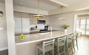 A modern kitchen with a central island, bar stools, and pendant lighting. - The Best Spot for Your Getaway — Terrace w/ Water View, Full Kitchen, and Pool (Duck Key)