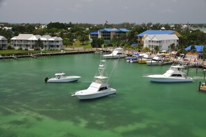 Ein Yachthafen mit mehreren weißen Booten, die vertäut sind, umgeben von Gebäuden mit blauen Dächern und freiem Blick auf das Wasser.