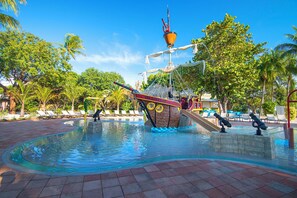 A swimming pool with a pirate ship-themed slide, lounge chairs, and palm trees. - Amazing Location in the Middle of Florida Keys — Full Kitchen and Onsite Pool (Duck Key)