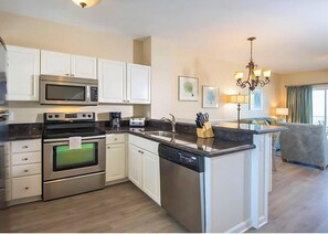 A modern kitchen with stainless steel appliances, white cabinetry, and a central island with a dishwasher. - Amazing Location in the Middle of Florida Keys — Full Kitchen and Onsite Pool (Duck Key)