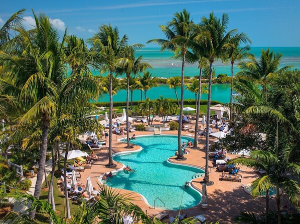 A resort pool area with multiple swimming pools, surrounded by palm trees and lounge chairs. - Amazing Location in the Middle of Florida Keys! Full Kitchen! Onsite Pools (Duck Key)