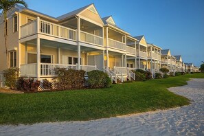 A row of beachside bungalows with balconies, a sandy walkway, and a clear blue sky. - A Place You'll Surely Enjoy! Full Kitchen, Outdoor Swimming Pool Near Key West (Duck Key)