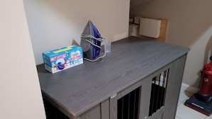 A room with a grey cabinet, a vacuum cleaner, and a box of Fairy Big One detergent.