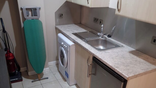 A compact kitchen with a washing machine, a sink, and a dishwasher.