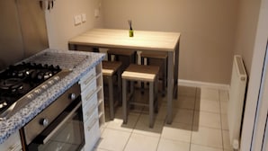 A compact kitchen with a gas stove, oven, and a dining table with benches.