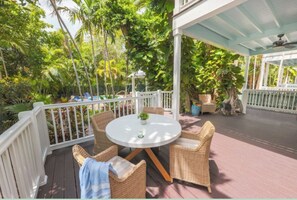 A covered outdoor seating area with wicker furniture and a round table, surrounded by lush greenery. - Serene Stay – Private Pool & Full Kitchen Near Key Largo (Duck Key)