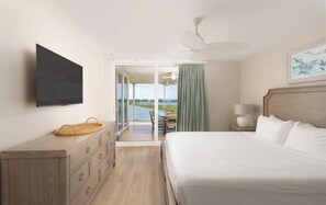 Ein Hotelzimmer mit Bett, Fernseher, Kommode, Nachttisch, Lampe und Blick ins Freie.