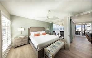 A hotel room with a bed, bedside table, lamp, and a view of the balcony and outside. - Fully Equipped Kitchen and Pool Access Make This an Easy Choice for your Stay (Duck Key)