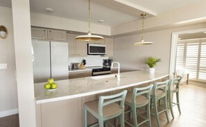A modern kitchen with a central island, bar stools, and pendant lighting. - Everything you Need for Comfort: Pool Access and Full Kitchen - Near Key West (Duck Key)