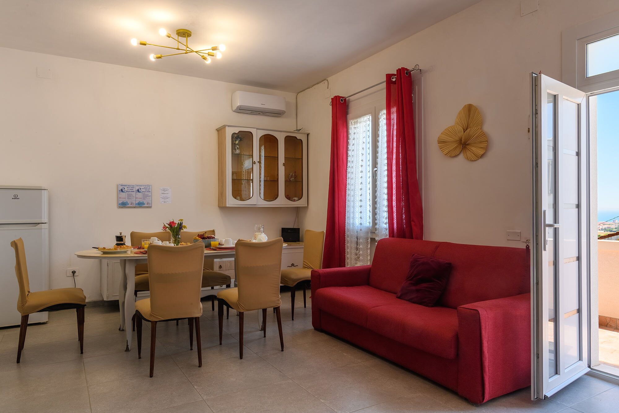 A dining area with a table, chairs, and a red sofa.