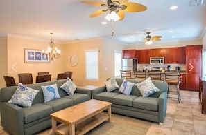 A modern living room with a green sofa set, wooden coffee table, and a dining area with chairs and a chandelier. - A Perfect Mix of Comfort and Convenience with Pool Access and Full Kitchen! (Duck Key)