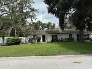 Une maison de plain-pied avec une pelouse devant, un garage et une allée.