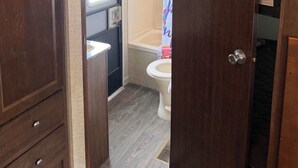 Baño compacto para autocaravana con inodoro, cabina de ducha y una pequeña zona de lavabo.
