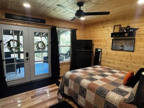 A cozy room with a bed, a ceiling fan, a television, and a sign above the door. - Wolf Creek Cabin Waterfront/Secluded/Firepit/VA Creeper Trail/South Holston Lake (Abingdon)
