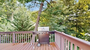A barbecue grill on a wooden deck with a view of trees. - Lake Lure Lakefront House, Private Dock, Multiple Decks, Kayaks, Mountain Views, Gameroom (Lake Lure)