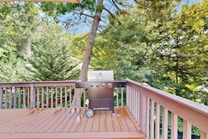 A barbecue grill on a wooden deck with a view of trees. - Lake Lure Lakefront House, Private Dock, Multiple Decks, Kayaks, Mountain Views, Gameroom (Lake Lure)