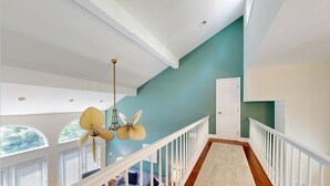 A spacious interior with a high ceiling, a staircase with white railings, and a view of the outdoors through a large window. - Lake Lure Lakefront House, Private Dock, Multiple Decks, Kayaks, Mountain Views, Gameroom (Lake Lure)
