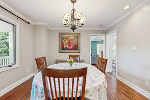 A dining area with a round table, chairs, a chandelier, and a painting on the wall. - Lake Lure Lakefront House, Private Dock, Multiple Decks, Kayaks, Mountain Views, Gameroom (Lake Lure)