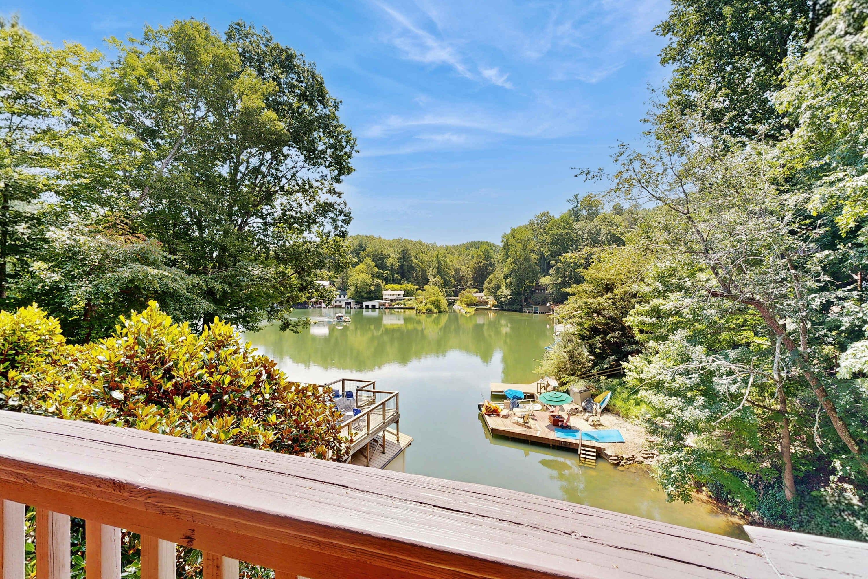 A lakeside view with a wooden deck, dock, and boats.
