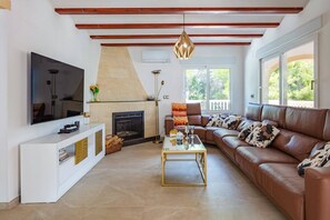 Ein Wohnzimmer mit Kamin, einer Couch, einem Couchtisch und einem Fernseher.
