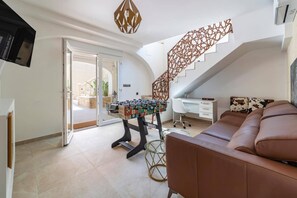 A modern living room with a foosball table, a sofa, a desk, and a staircase. - Villa El Silencio by Villa Plus (Jávea)