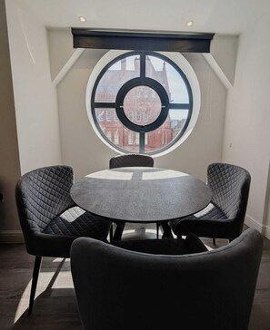 Een ronde tafel met vier stoelen in een kamer met een groot rond raam.