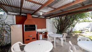 Un patio exterior con una parrilla, asientos y vistas del entorno.