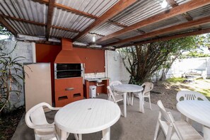 An outdoor patio with a grill, seating, and a view of the surrounding area. - Comfortable Apt 270m From the Beach Stcy101 (Florianópolis)